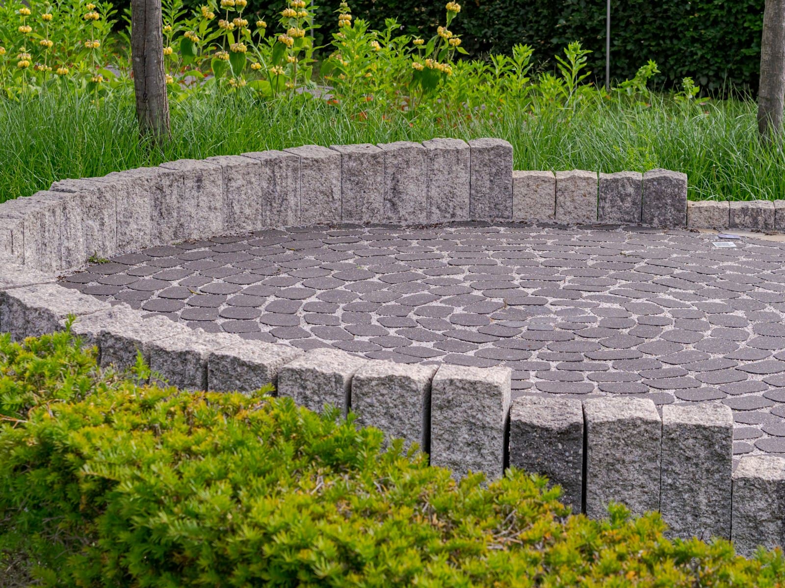 Circular paver patio with a low stone wall